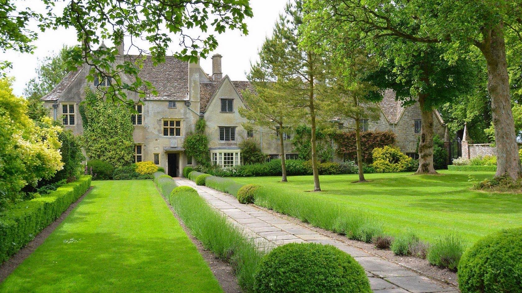 An established garden with a manicured lawn, clipped hedges and borders