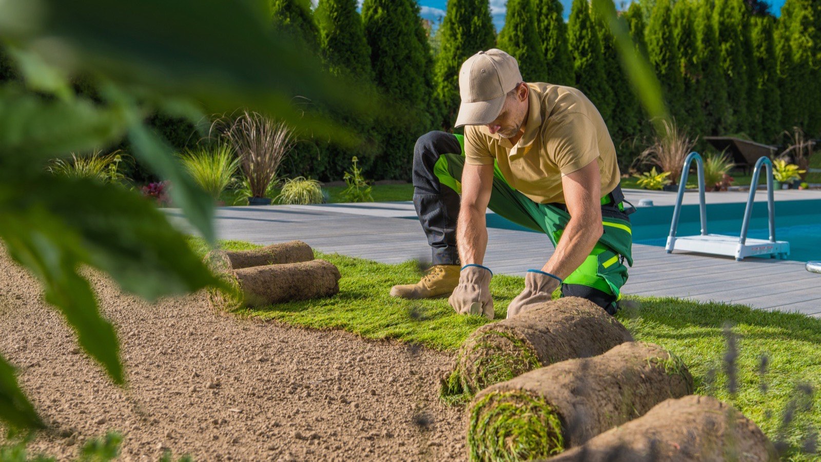 A landscaper laying rolls of new turf
